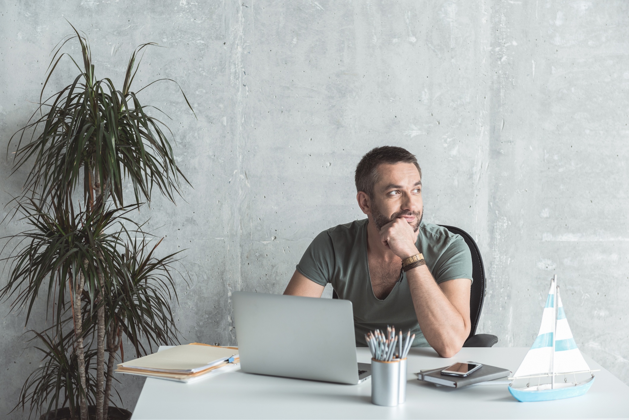 Pensive-man-with-stubble-is-laboring-in-office-869448100_2123x1417